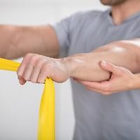 Nahaufnahme Mann mit ausgestreckten Armen und Gymnastikband wird von anderer Hand gestützt